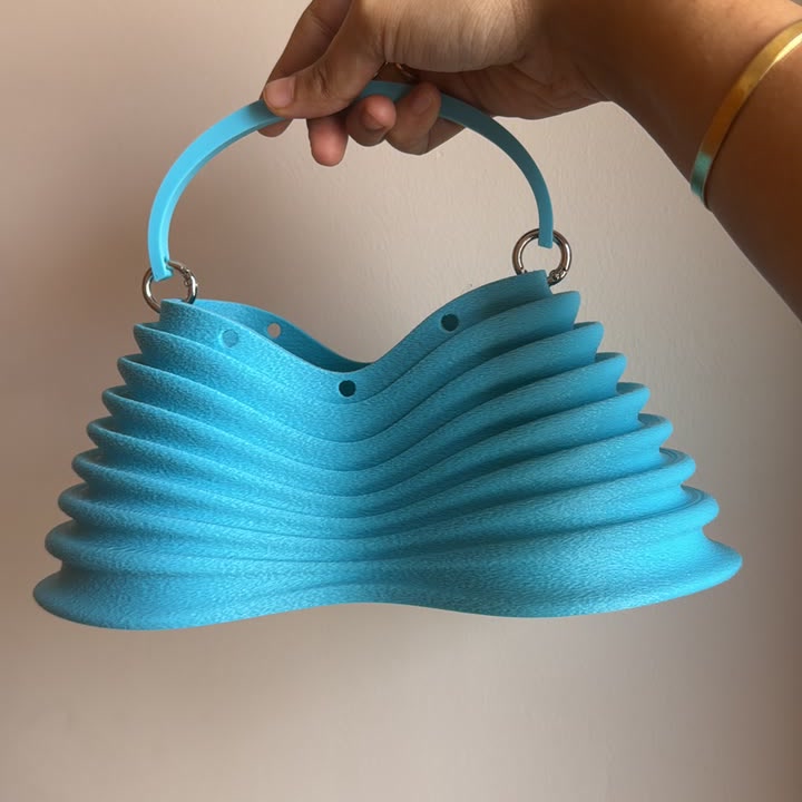 Thorax Bag in aqua blue, held by the handle