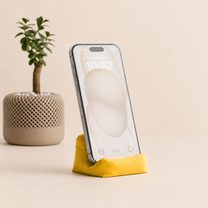 Cushion Bean Pod holding a phone in yellow, with a plant