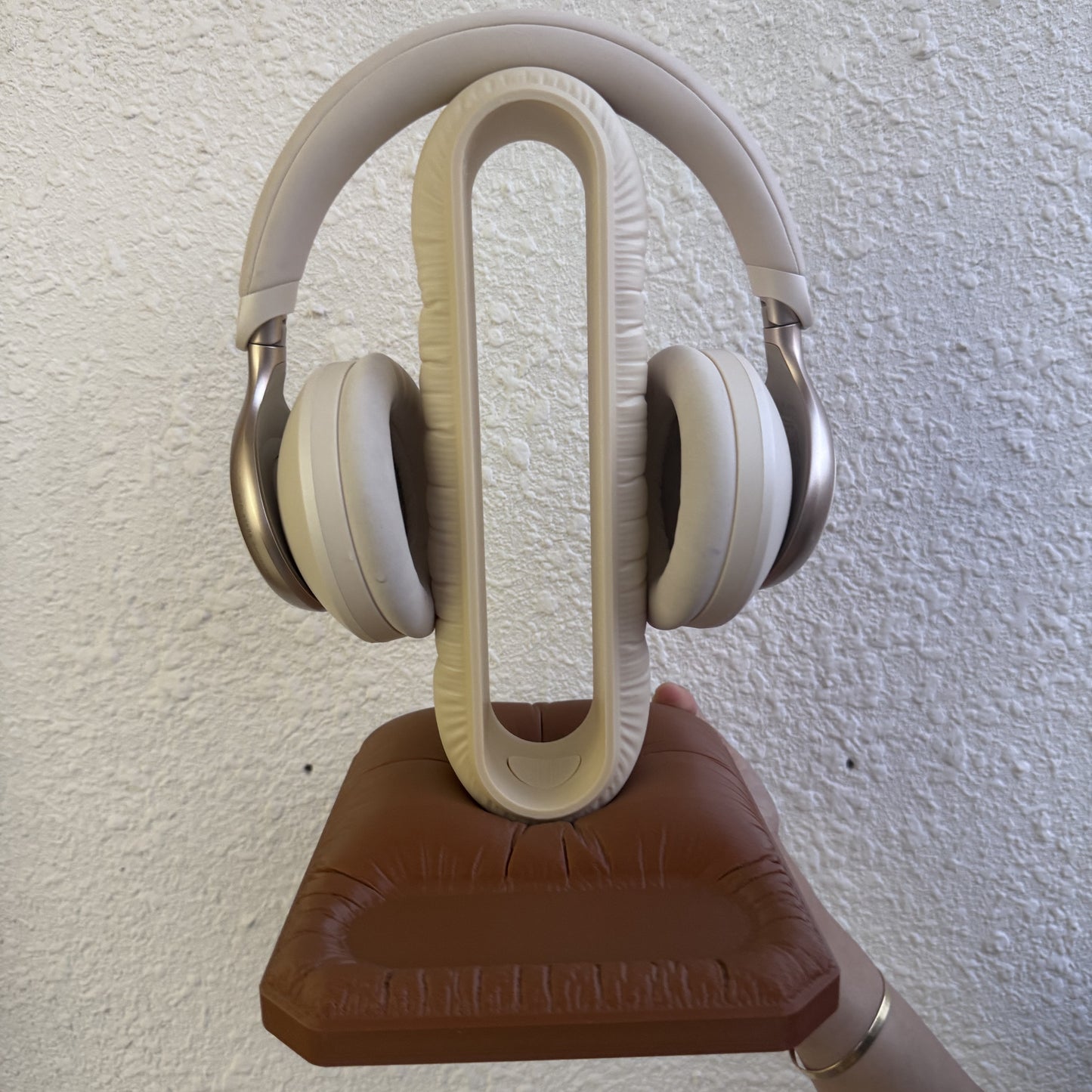 Cushion Headspace in beige-brown — cream arch on a brown pillow base, holding headphones