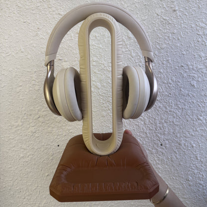 Cushion Headspace in beige-brown — cream arch on a brown pillow base, holding headphones