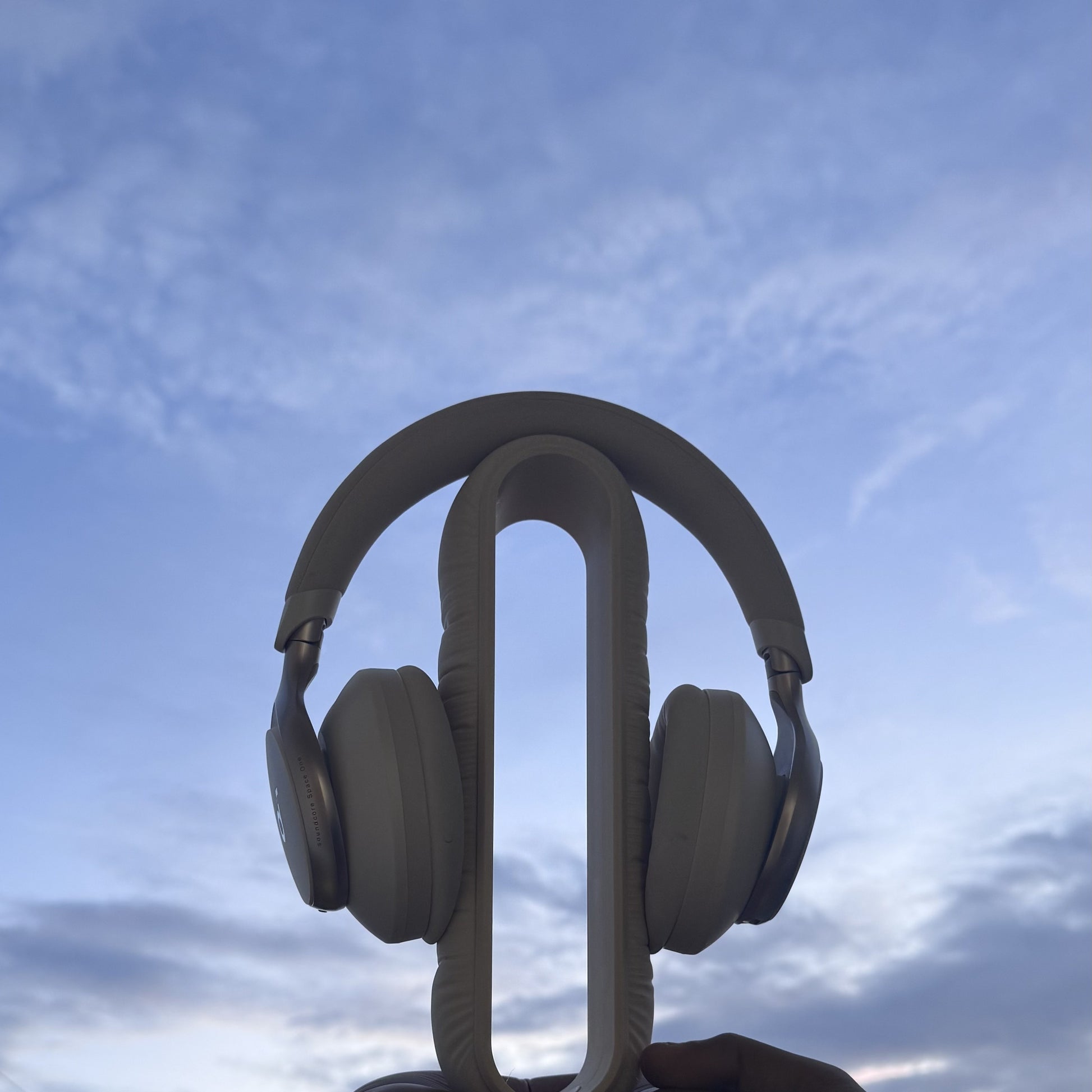 Cushion Headspace beige-brown headphone stand held against the sky