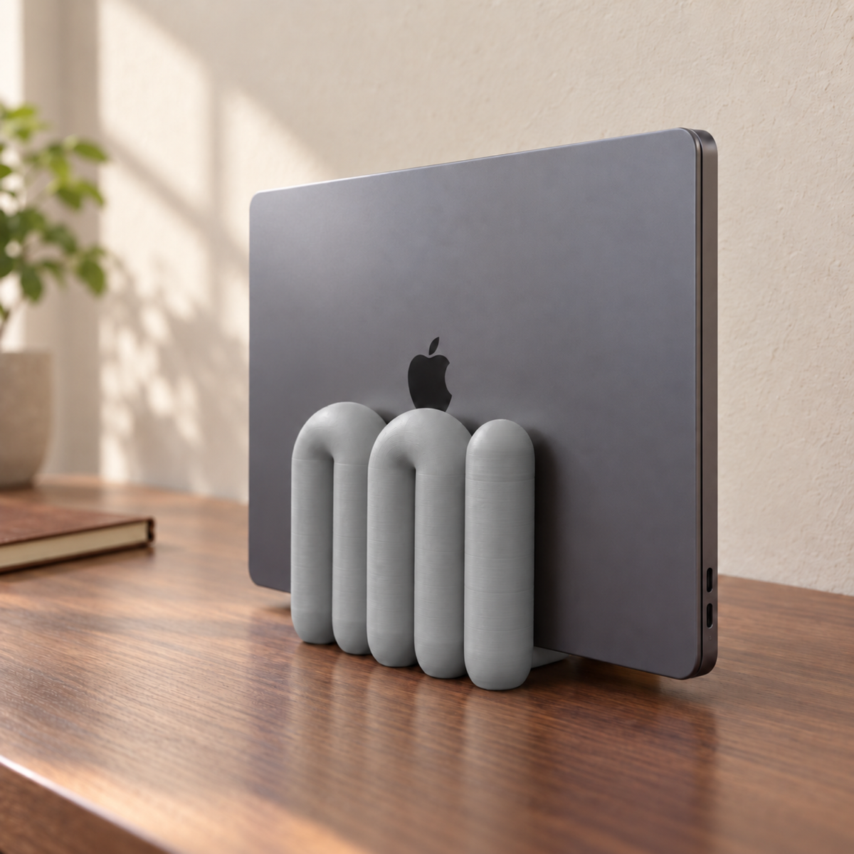The Loop Stand in grey holding a closed dark grey laptop, angled view