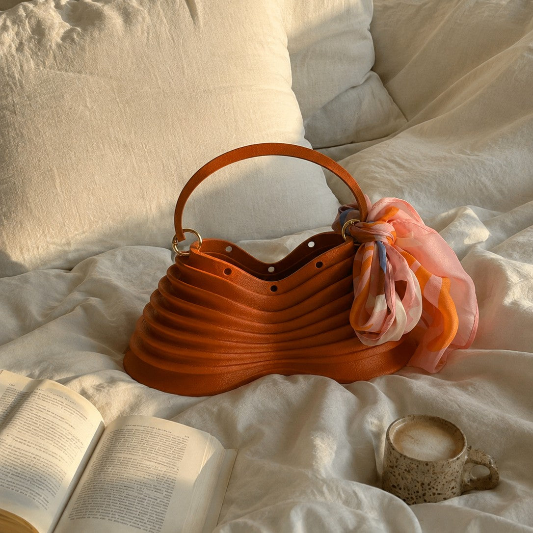 Thorax Bag styled on a bed with a book and coffee