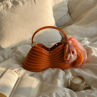 Thorax Bag styled on a bed with a book and coffee